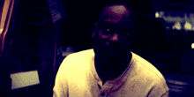 a man in a white shirt is looking at the camera with his eyes closed