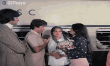 a woman is holding a bouquet of flowers while standing next to a man and a woman .