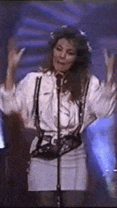a woman is standing in front of a microphone with her arms outstretched .