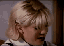 a close up of a woman 's face with blonde hair and a black nose .