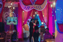 a woman in a red dress is dancing with a man in a black suit at a party