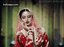 a woman in a red and gold dress and veil is looking down .