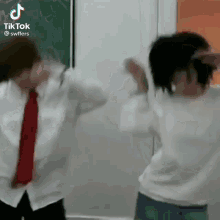 a man and a woman are dancing in a classroom in front of a blackboard .
