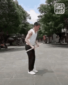 a man is standing on a sidewalk holding a stick in his hands .