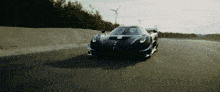 a black sports car is driving down a road