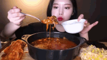 a woman is eating a pot of food with a spoon in her mouth