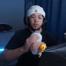 a man wearing a white hat with a bear on it is holding a yellow toy