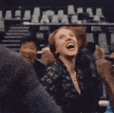 a woman is laughing in a crowd of people in a theater .