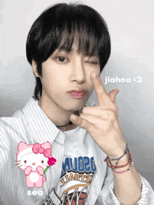a person with a hello kitty sticker on their shirt making a peace sign