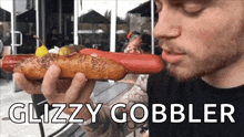 a man eating a hot dog with the words glizzy gobbler written below him