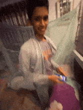 a young boy is sitting under a mosquito net playing a game on his phone .