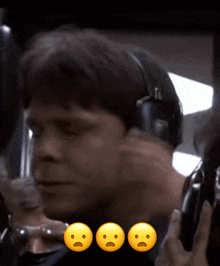 a man wearing headphones talks on a phone with three smiley faces on the bottom
