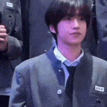 a young man in a suit and tie is standing in front of a crowd of people .