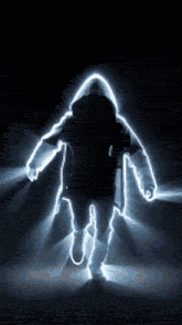 a silhouette of a person in a hooded jacket walking in the dark