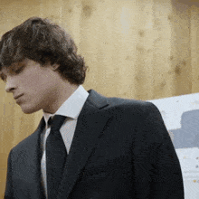 a young man in a suit and tie is looking down