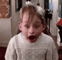 a young boy is making a funny face in a hallway .