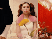 a woman in a white tank top is holding a flower