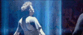 a man is standing in front of a blue curtain looking up