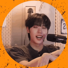 a young man is sitting in front of a microphone and laughing .