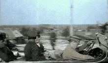 a black and white photo of a man driving a convertible