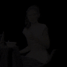 a woman is sitting at a table with a bowl of food and giving a thumbs up sign .