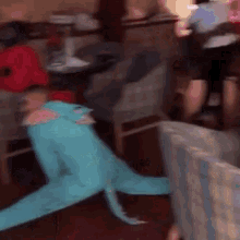 a person in a blue dinosaur costume is laying on the floor .