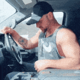 a man wearing a hat and a nike tank top is sitting in a car