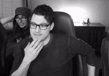 a black and white photo of a man wearing glasses and a woman in a hat