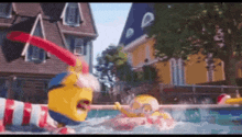 a couple of minions are swimming in a pool with a house in the background .