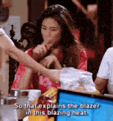 a woman in a red robe is sitting at a table with other people and the caption explains the blazer