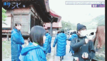 a group of women wearing blue coats are walking down a sidewalk
