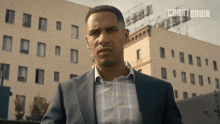 a man in a suit stands in front of a building with countdown written on the bottom