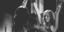 a black and white photo of two women dancing in a dark room .
