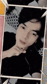 a man in a black shirt is laying on a bed with his hand on his chin