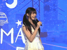 a girl singing into a microphone in front of a blue background that says ma