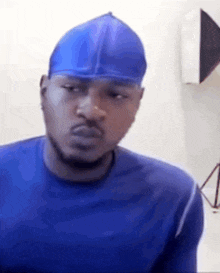 a man wearing a blue shirt and a blue hat is making a funny face .