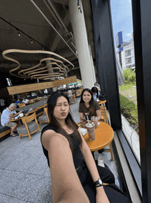 two women are sitting at a table in a restaurant and one is wearing a watch that says rolex