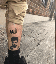 a man has a tattoo of a man and the word saw on his leg