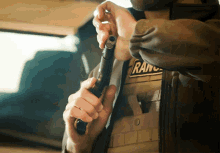 a man wearing a vest with the word ranch on it is holding a gun