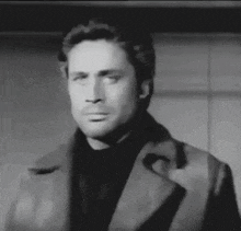 a black and white photo of a man wearing a coat and a black shirt