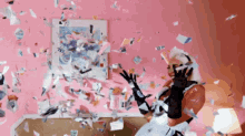 a woman in black gloves is standing in front of a pink wall surrounded by confetti