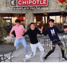 a group of young men are dancing in front of a chipotle restaurant