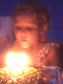 a little girl is blowing out a candle on a birthday cake