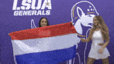 two women holding a flag in front of a lsua generals sign