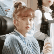 a woman in a sweater is sitting in a chair holding a glass of water .