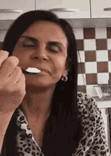 a woman is eating a spoonful of food in a kitchen .