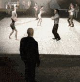 a man stands in front of a group of people dancing on a stage