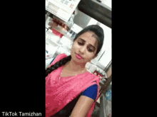 a woman in a pink saree and blue blouse is standing in a room .