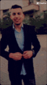 a man in a suit and a blue shirt is standing in front of a building with the word capcut on the bottom