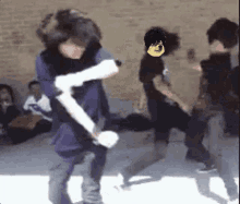 a group of people are dancing in front of a brick wall and one of them has a yellow face on his head